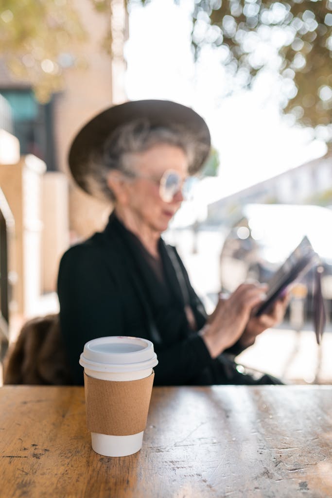Elderly Woman Sitting By The Table With A Cup Of Coffee