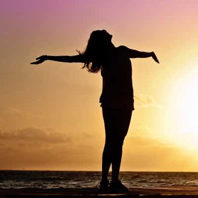 Woman meditating on beach at sunset