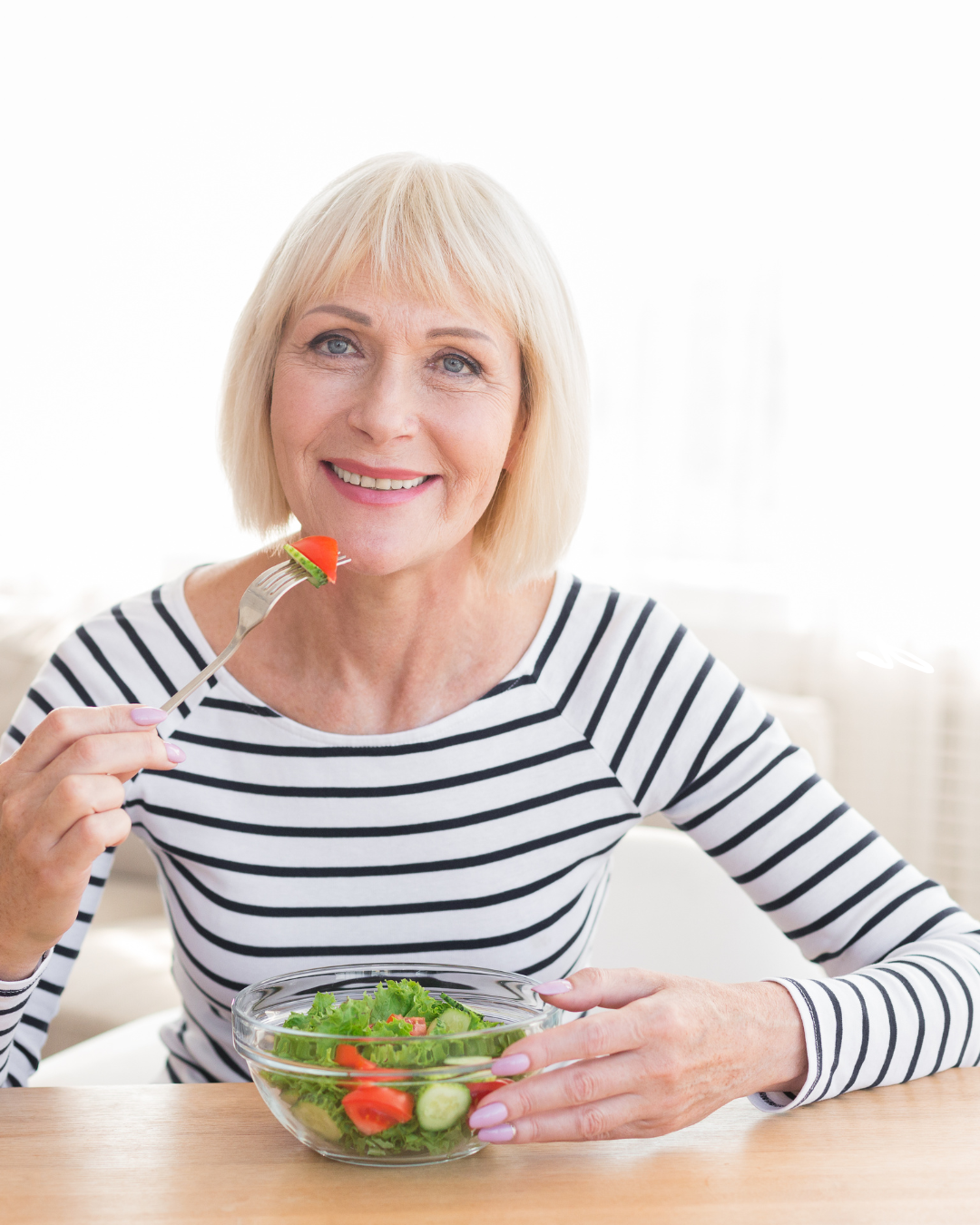 Woman in a stripy top eating a bowl of salad