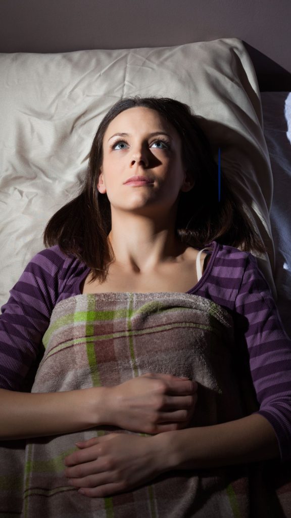 A woman trying to sleep but with her eyes open 